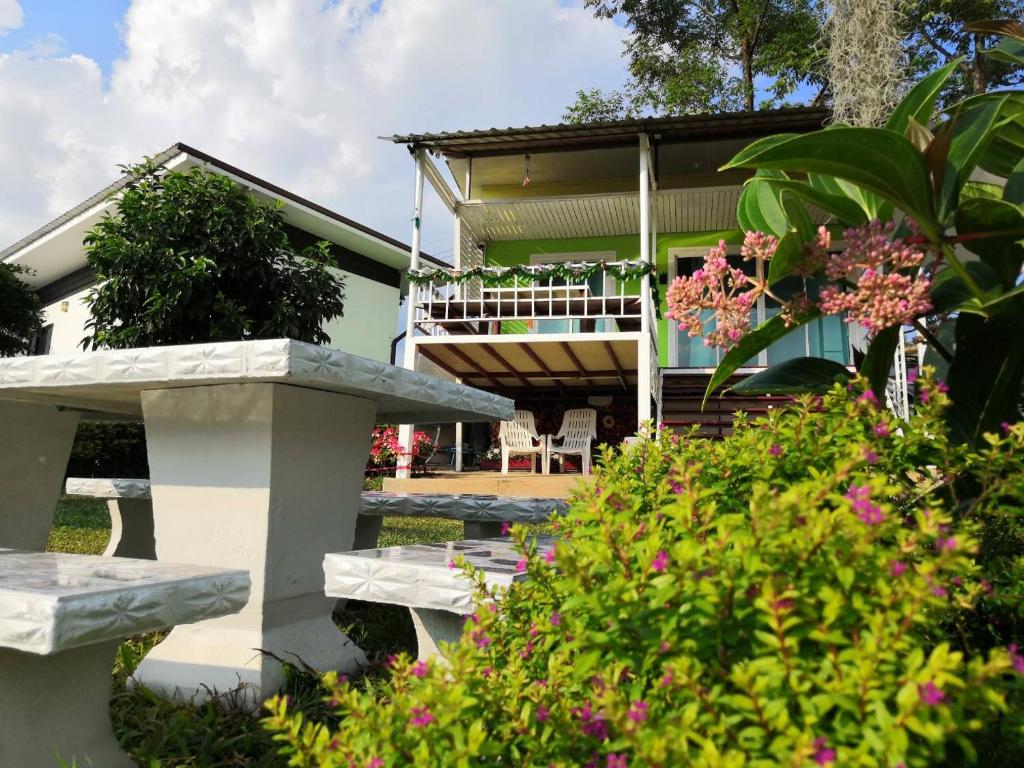 a house with a bench and flowers in front of it at บ้านปลายฝัน Baanplaifun in Ban Huai Phai