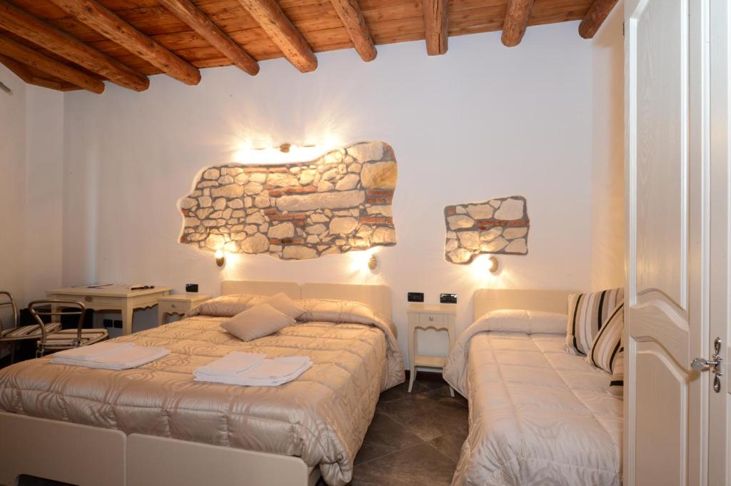 sypialnia z 2 łóżkami i kamienną ścianą w obiekcie CQ Rooms Verona w Weronie