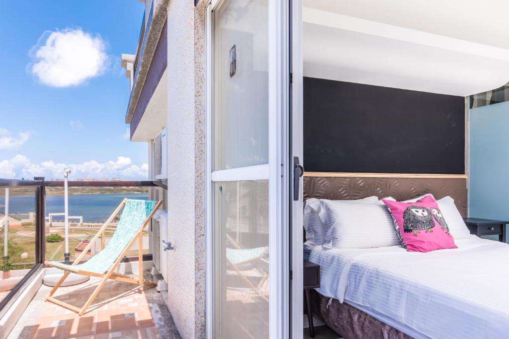 a bedroom with a bed and a balcony with a view of the ocean at Malibu OceanView Homestay in Magong