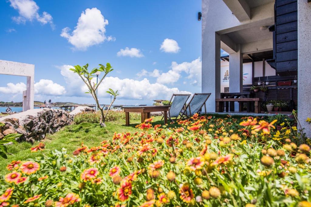 a garden with flowers in the grass next to a house at Malibu OceanView Homestay in Magong