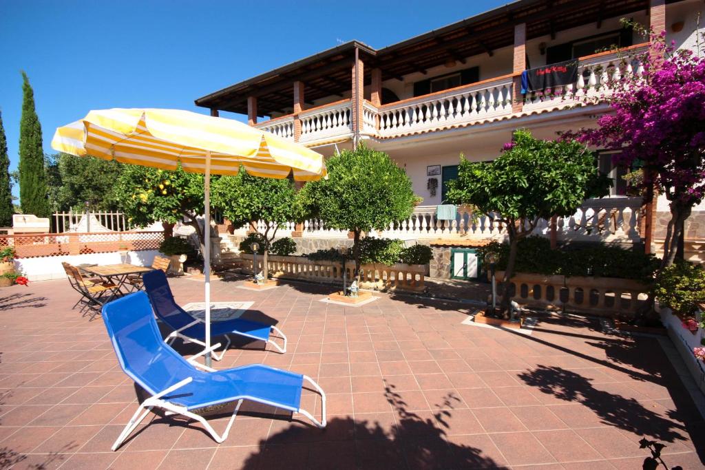dwa niebieskie krzesła i parasol na patio w obiekcie Baia Luna w mieście Marina di Camerota