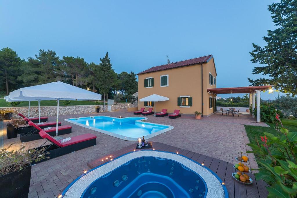 un patio trasero con piscina y una casa en Villa Primorje, en Biograd na Moru
