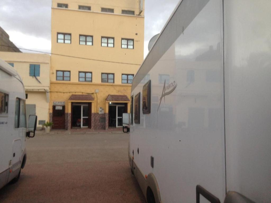 Hotel El ghazi في Villa Bens: اثنين من الشاحنات البيضاء تقف أمام المبنى