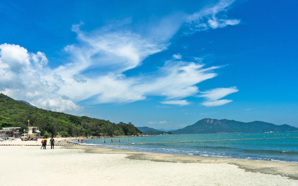 a group of people walking on the beach at The Cove Hostel - Tong Fuk Octopus in Hong Kong