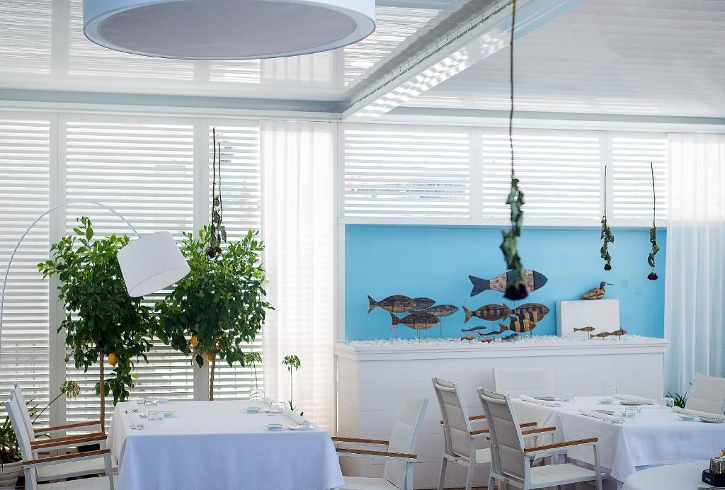 a dining room with white tables and chairs and a fish picture at Relais Maresca Luxury Small Hotel & Terrace Restaurant in Capri