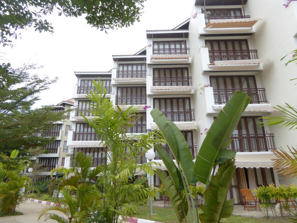 a tall white building with balconies and trees at The Orchid Beach Resort @ VIP Chain Resort in Ban Phe