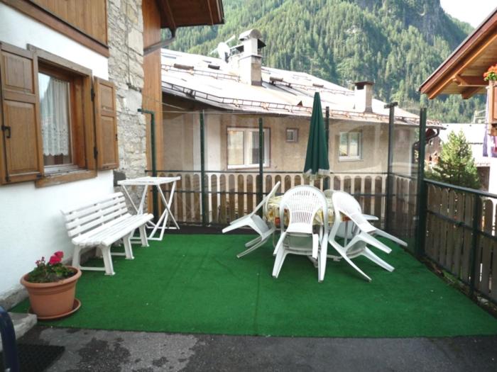 a patio with white chairs and a table and umbrella at Cesa Monica in Canazei