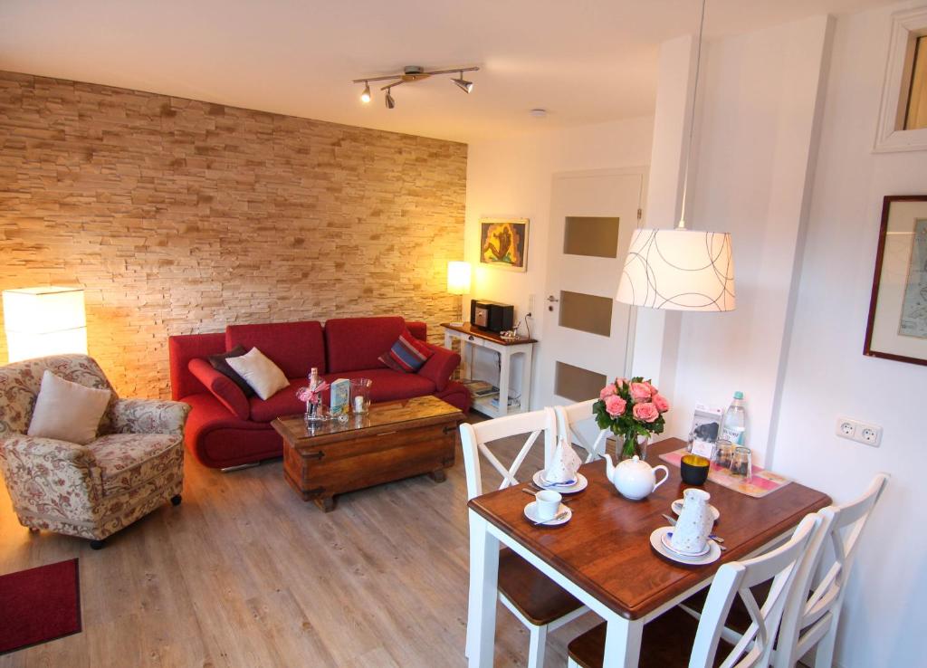 ein Wohnzimmer mit einem Tisch und einem roten Sofa in der Unterkunft Ferienwohnung Lukas Bockelmann´s Hof (ebenerdig) in Westerland