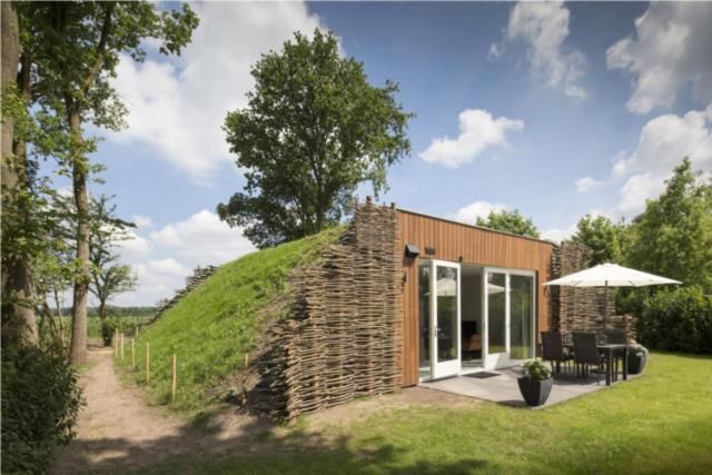 una pequeña casa de ladrillo con una colina de hierba en Onderlandhuis 38 en Chaam