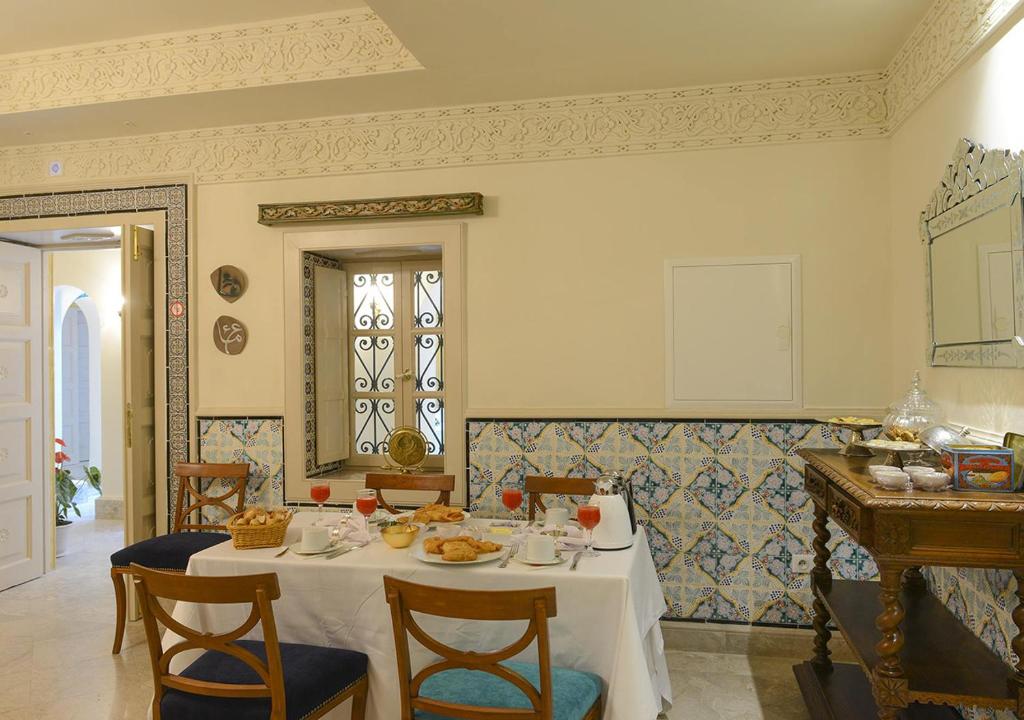 a dining room with a white table and chairs at Dar ALOUINI in Kairouan