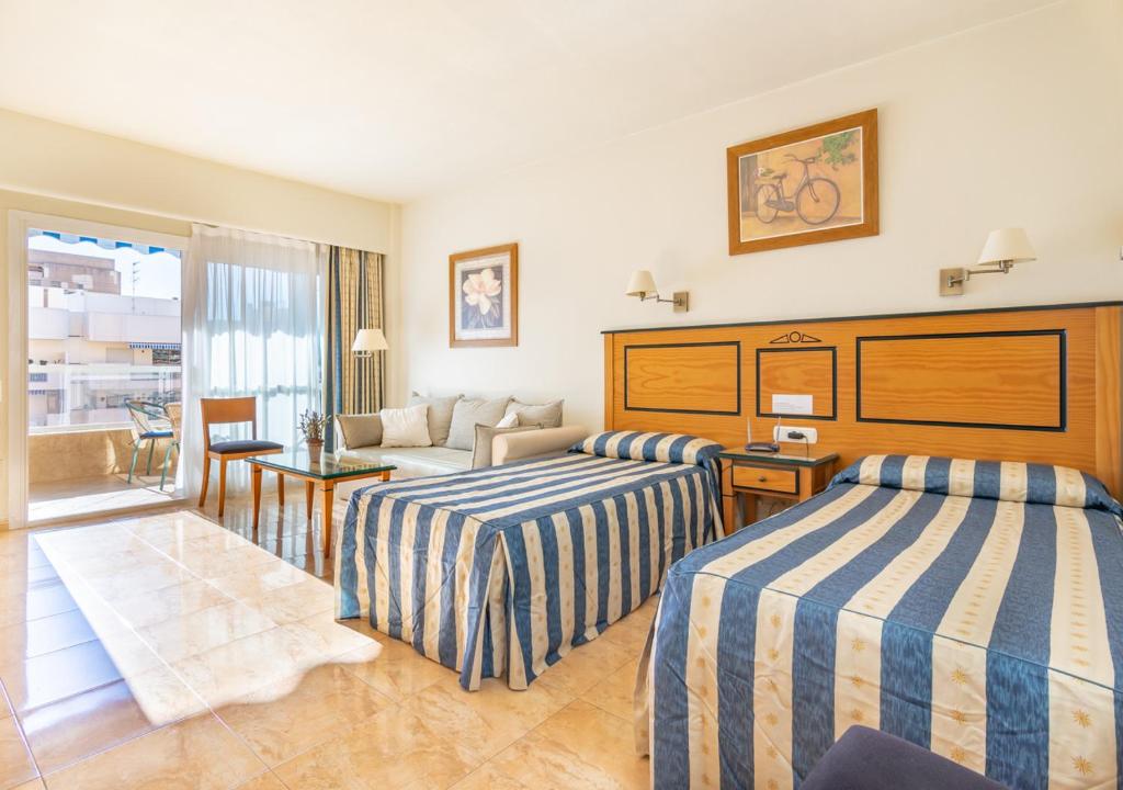 フエンヒロラにあるStudio PYR Fuengirola frente al marのベッド2台とソファが備わるホテルルームです。