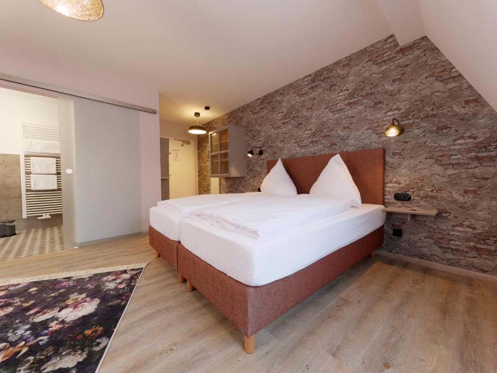 a bedroom with a large bed and a brick wall at Hotel - Weinbar FAHR AWAY in Volkach