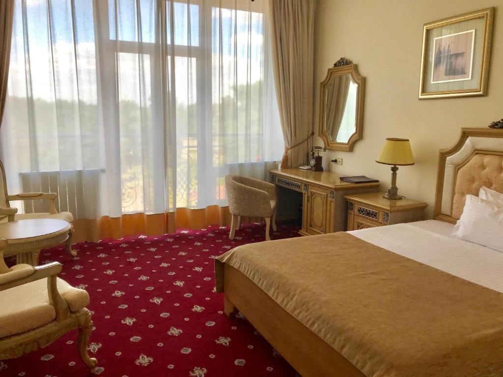 a hotel room with a bed and a desk and a mirror at Visak Hotel in Kyiv