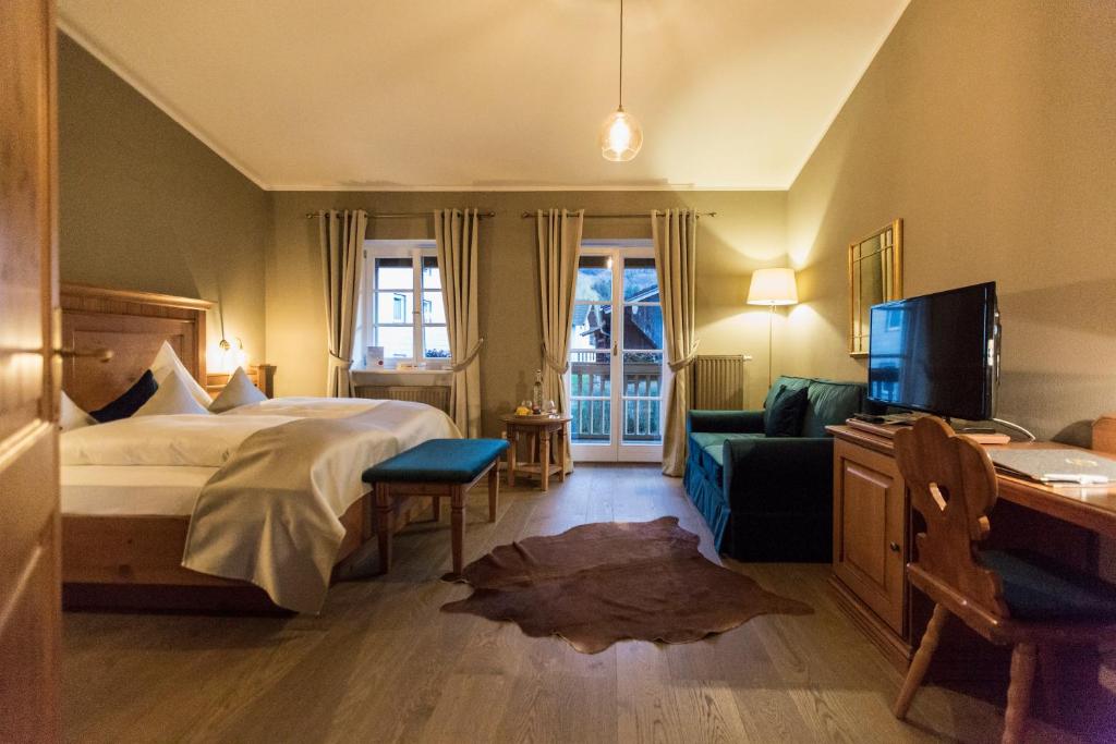 ein Hotelzimmer mit einem Bett, einem Sofa und einem TV in der Unterkunft Landgasthof Karner in Frasdorf