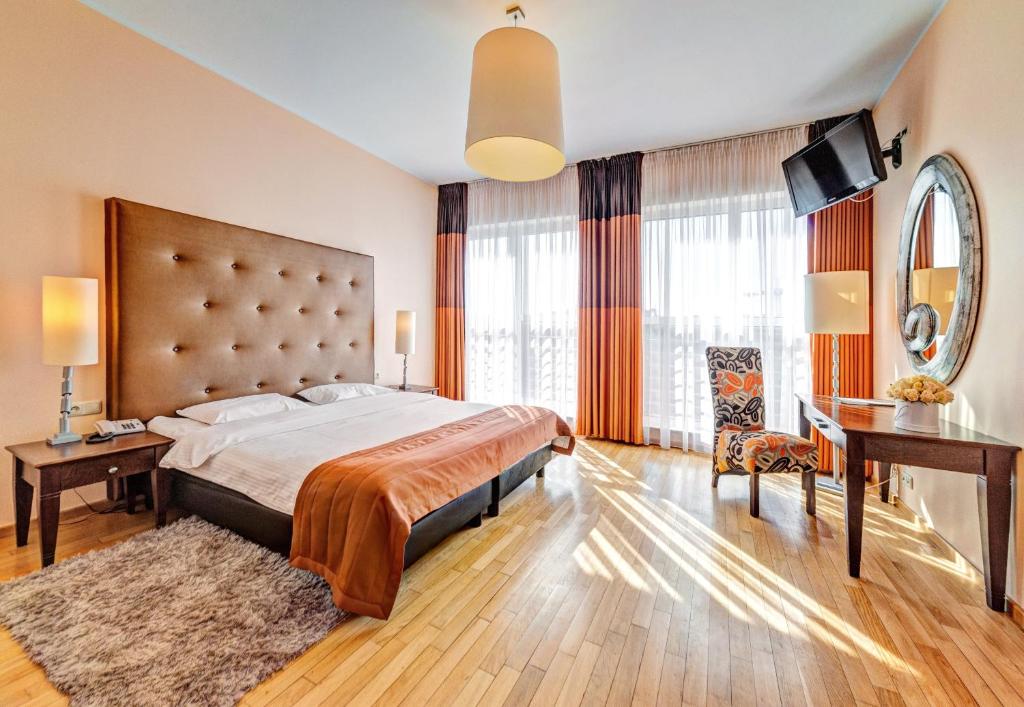 a bedroom with a large bed and a desk at Don Prestige Residence in Poznań