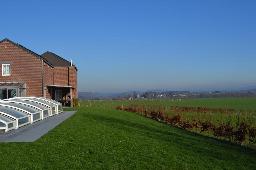 a building with a greenhouse on the side of a field at Vue d'en Haut in Durbuy