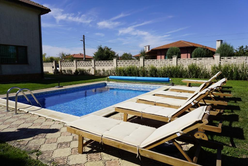 a swimming pool with lounge chairs and a swimming pool at Вила Калиакра - Villa Kaliakra - 3 km to beach Bolata in Bŭlgarevo