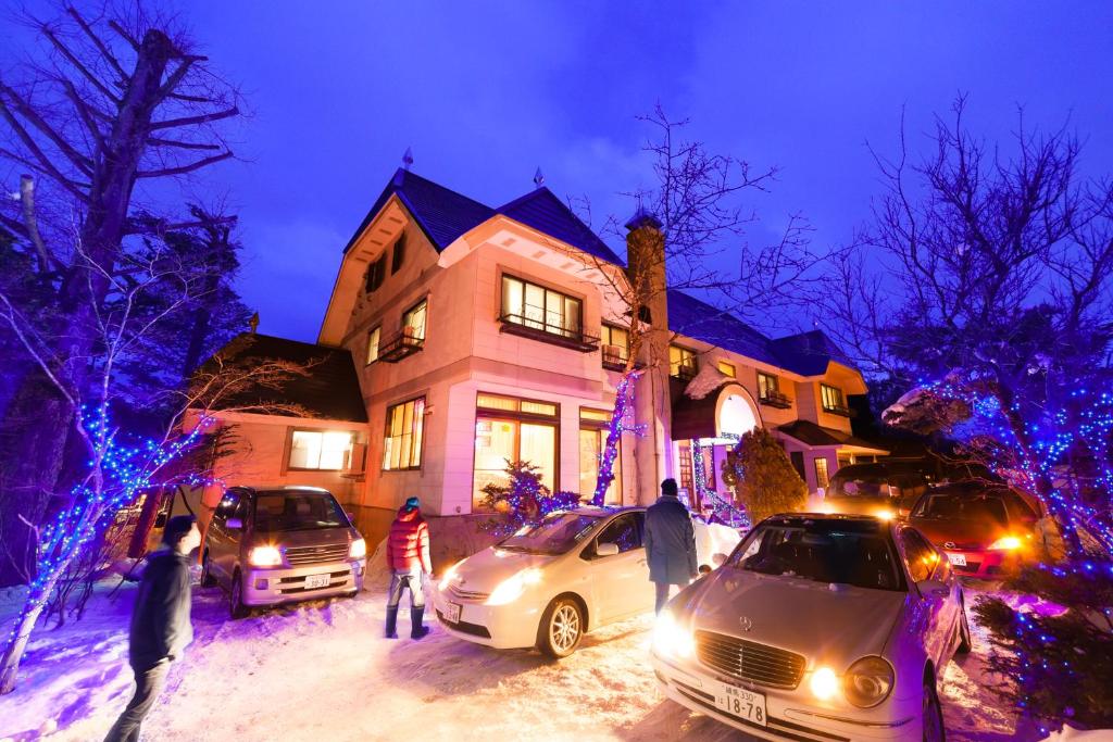 a house with cars parked in the snow at night at Petit Hotel P-Bow in Hakuba