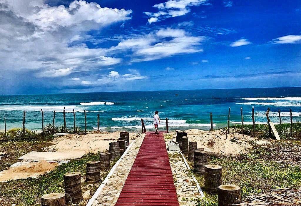 een persoon die over een rode promenade op het strand loopt bij Casa Taíba Beach Resort in Taíba