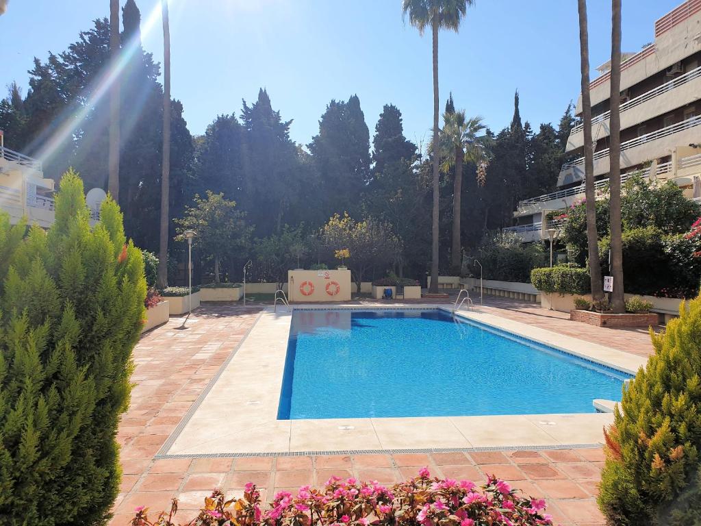 una piscina in un cortile con fiori e alberi di Spacious 3 Bedroom 2nd Line Beach Apartment Marbella Center a Marbella