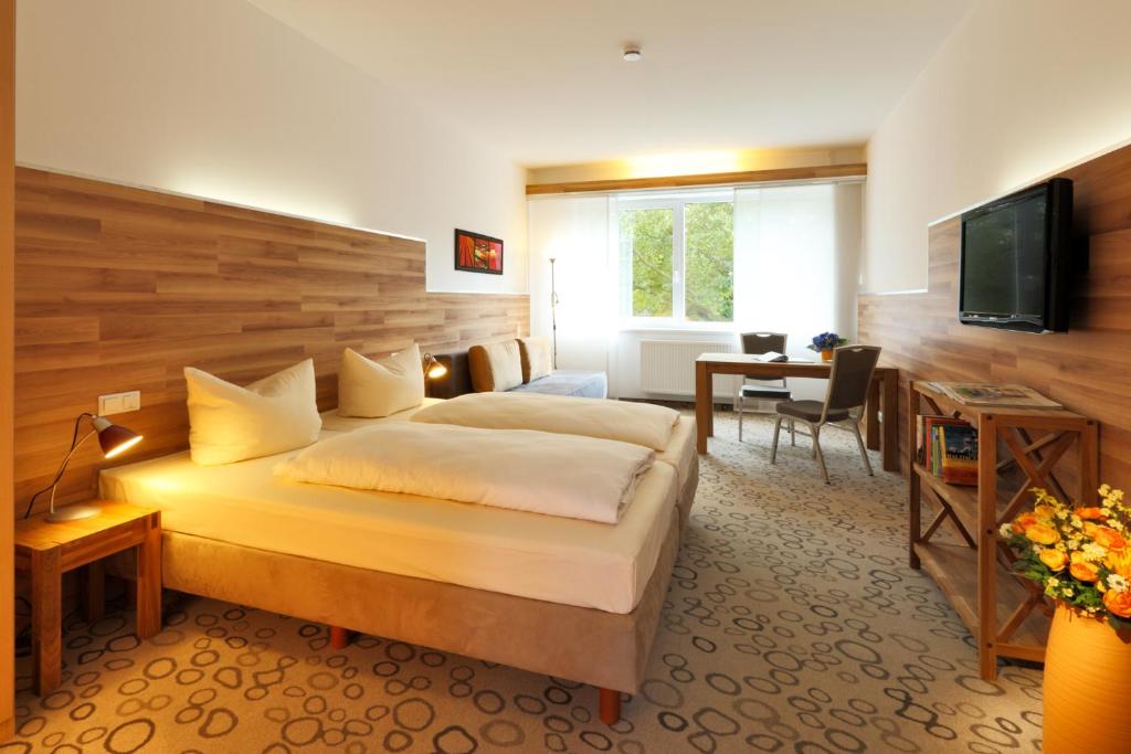 a hotel room with a bed and a desk and a television at Petul Apart Hotel Am Ruhrbogen in Bochum