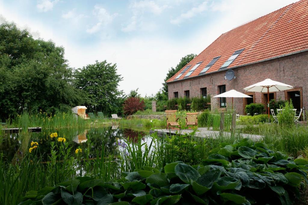 um jardim com um lago em frente a um edifício em Lindenhof Gästehaus & Hofcafe em Kranenburg