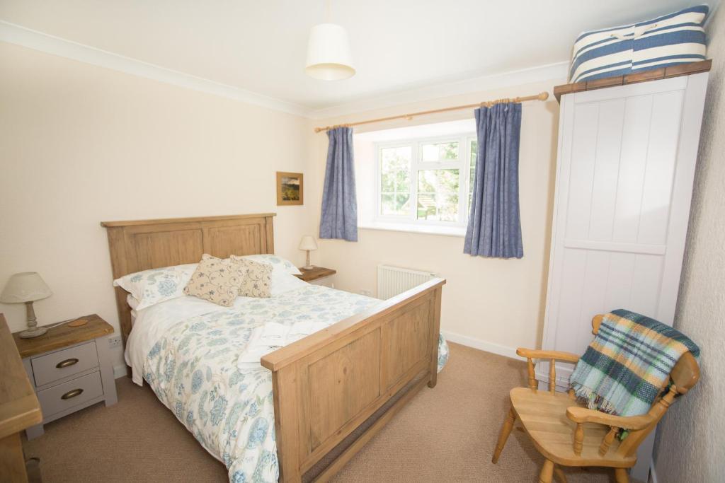 sypialnia z łóżkiem, krzesłem i oknem w obiekcie Stable Cottage w mieście Bardon Mill