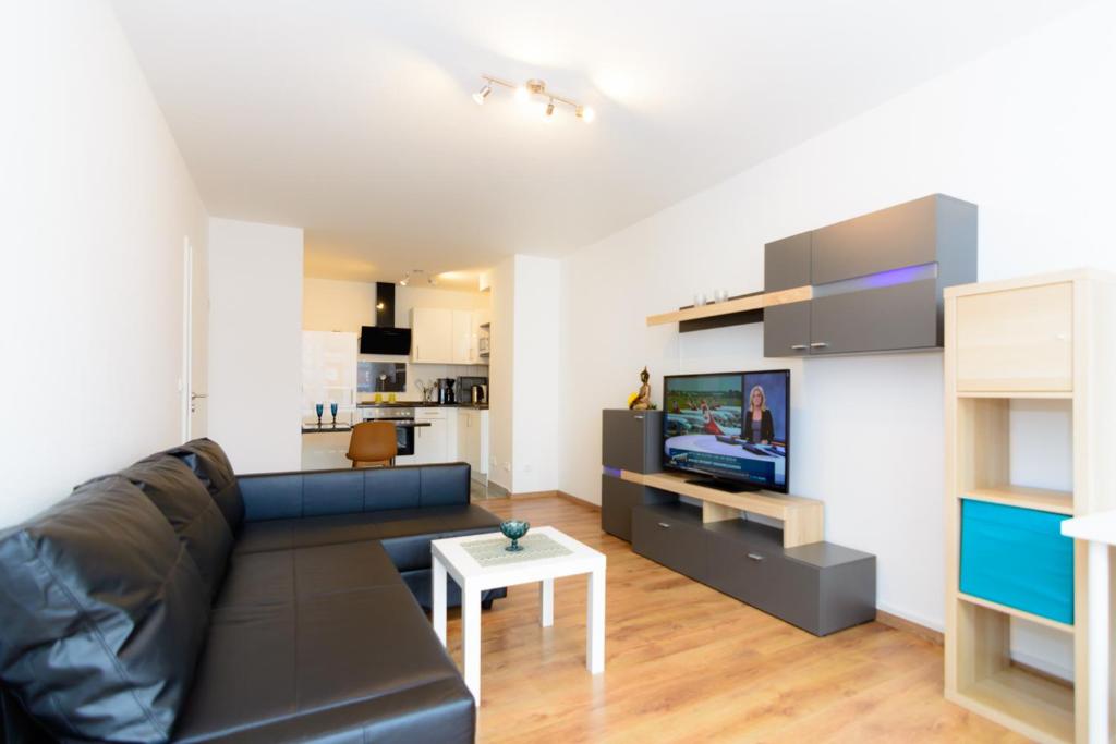 un soggiorno con divano in pelle nera e TV di Private apartments close to subway a Norimberga