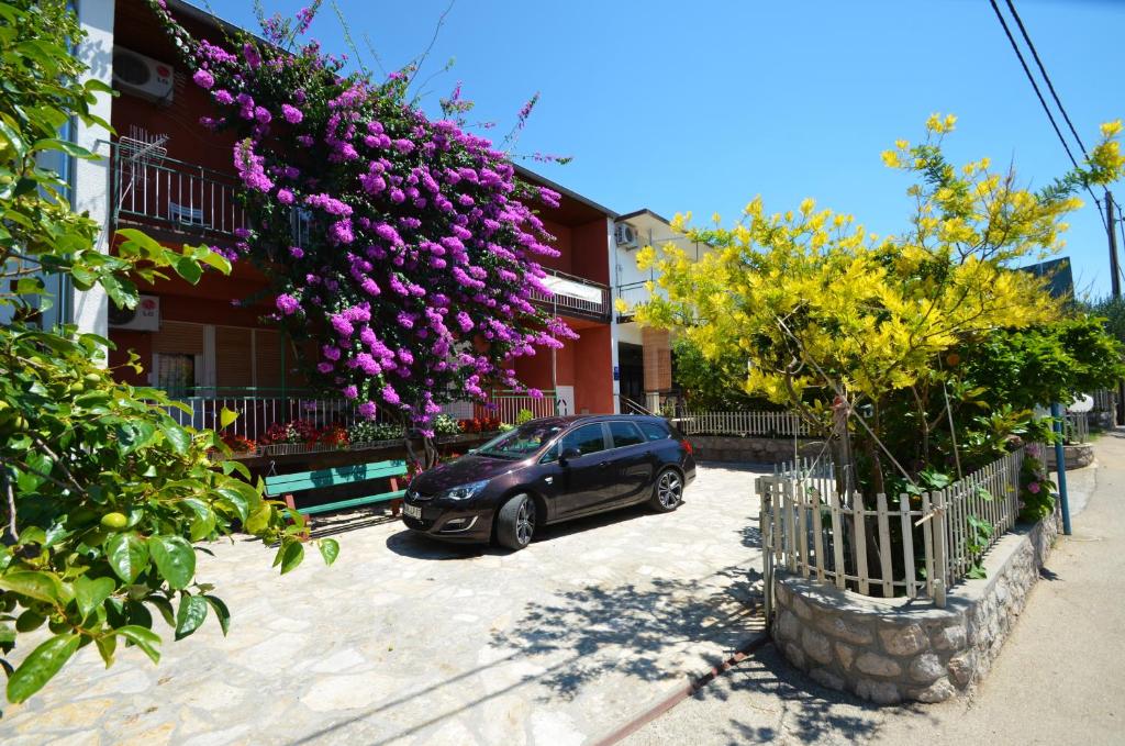 a car parked in front of a building with purple flowers at Guest House Tinka in Starigrad