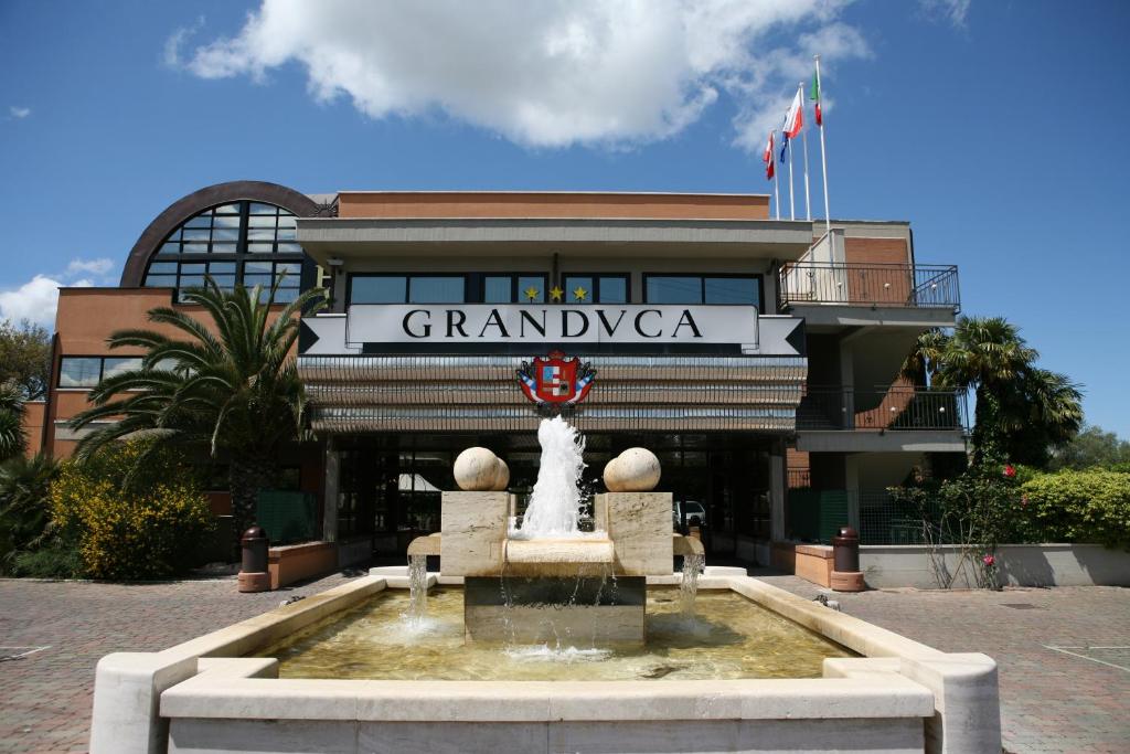 a building with a fountain and a statue in front of it at Hotel Granduca in Grosseto