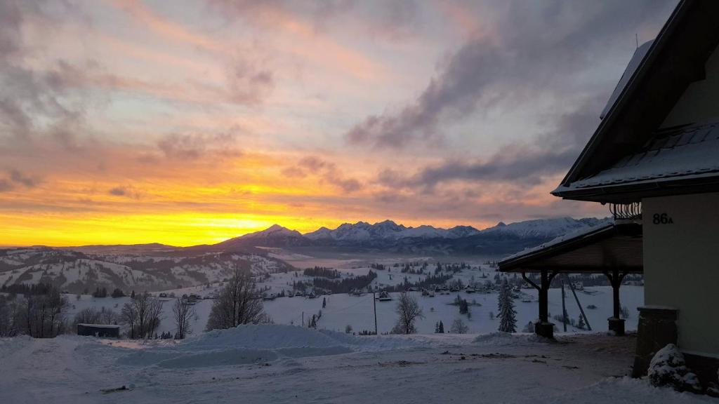 a sunset in the mountains with snow on the ground at Villa Julia - apartamenty widokowe in Biały Dunajec