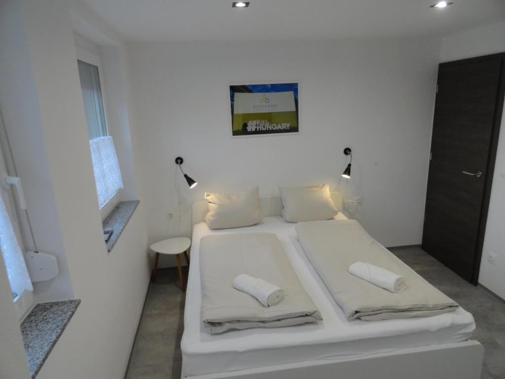 białe łóżko w białym pokoju z 2 poduszkami w obiekcie Trenta Apartman Bükfürdő w mieście Bük