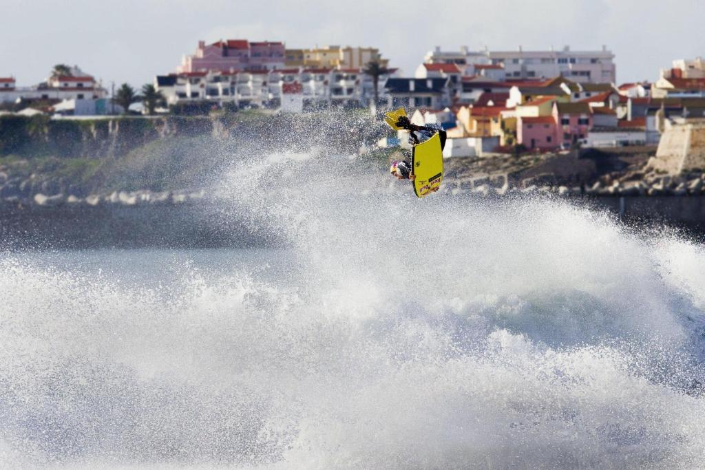 un homme faisant une vague sur une planche de surf dans l'eau dans l'établissement Casa do Gato que queria ser Pescador, à Peniche
