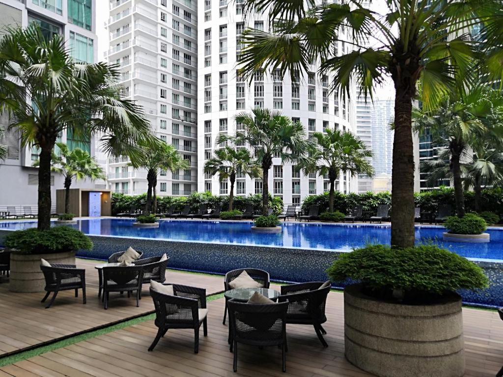 a courtyard with tables and chairs and palm trees at Soho Suites KLCC by C&C Fortune in Kuala Lumpur