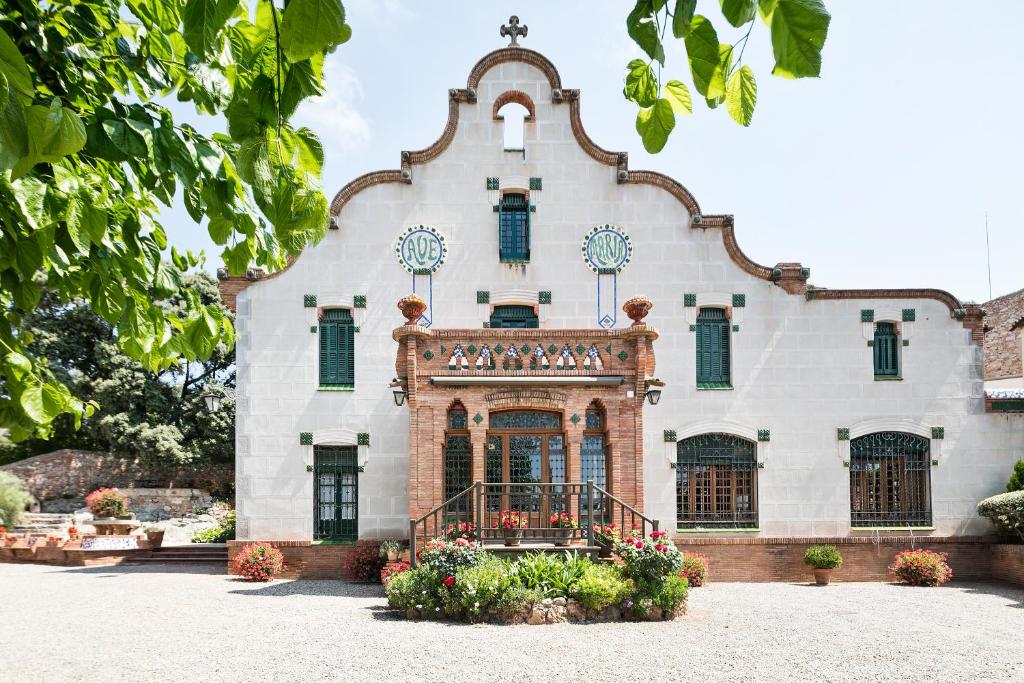 een groot wit gebouw met groene luiken bij Can Borrell in Castellar