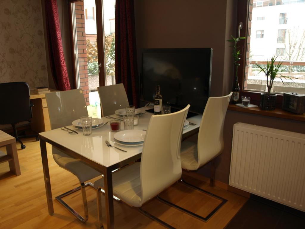 uma mesa de jantar com cadeiras brancas e uma televisão em Apartament przy parku em Breslávia