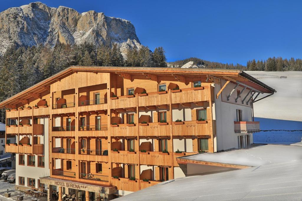 un grand bâtiment avec une montagne en arrière-plan dans l'établissement Hotel Serena, à Badia