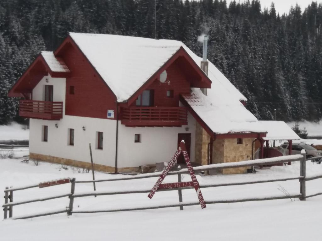 un granero rojo y blanco con techo cubierto de nieve en Pensiunea Agroturistica Alexandra, en Smida