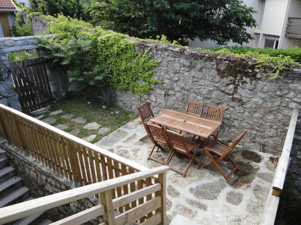 une table et des chaises en bois à côté d'un mur en pierre dans l'établissement La Mare aux oiseaux 1608, à Sassenage