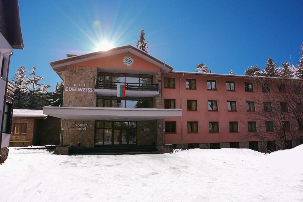 a building in the snow with the sun behind it at Hotel Borovets Edelweiss in Borovets