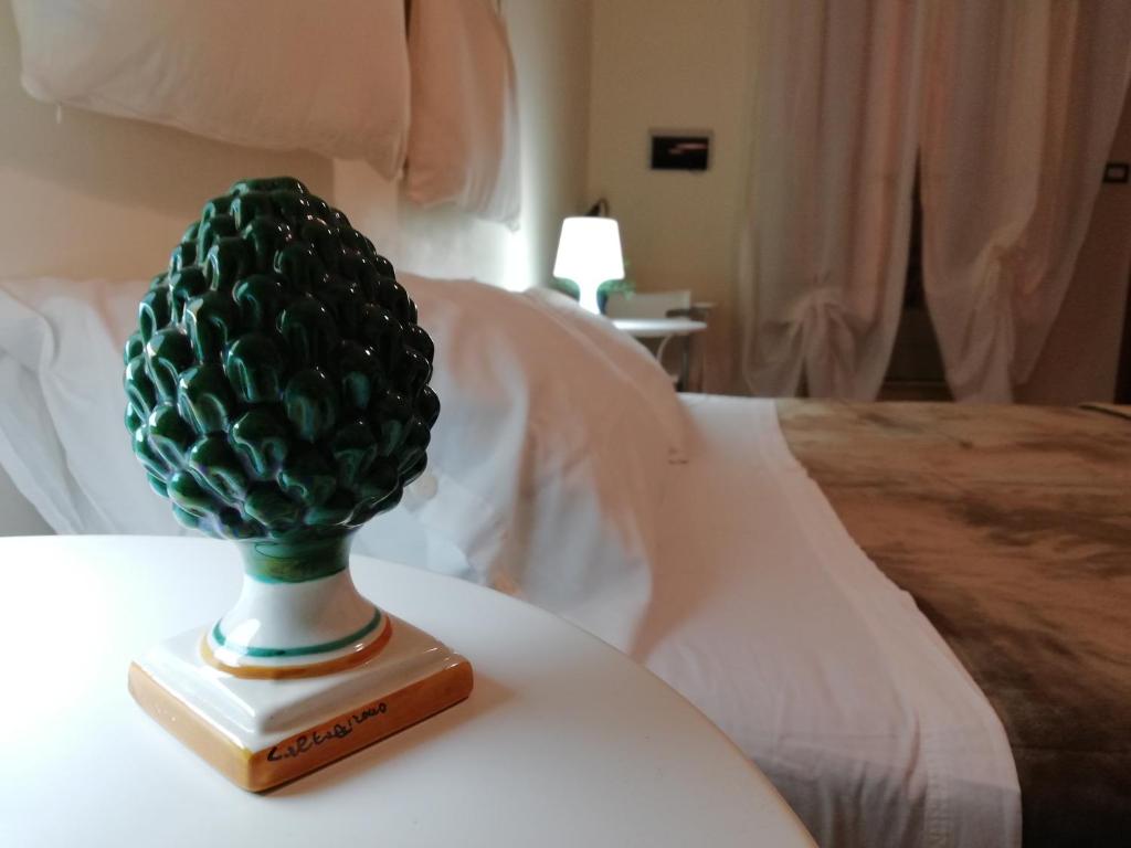 zielony ananas siedzący na stole obok łóżka w obiekcie Il Duomo Home w mieście Caltagirone
