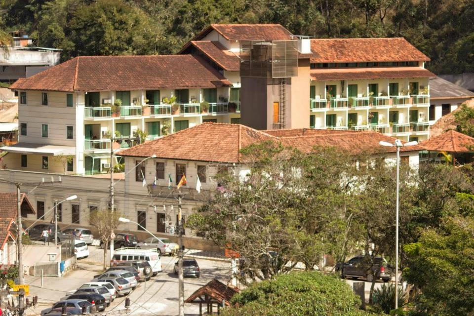 ein Gebäude mit Autos auf einem Parkplatz in der Unterkunft Hotel Dominguez Plaza in Nova Friburgo