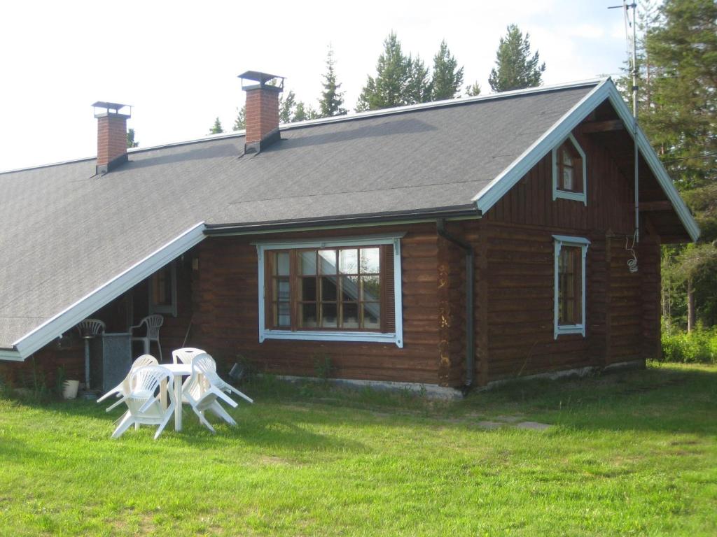 una casa con dos sillas blancas delante en Ruka-Kitkan lomamajat, en Käylä