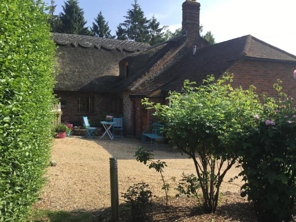una vecchia casa di mattoni con un patio e un cortile di Thatched Cottage a Pulborough