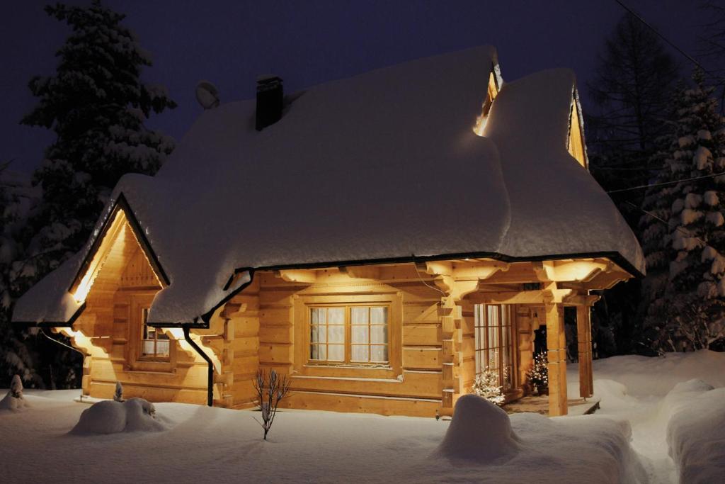 a log cabin covered in snow at night at BIAŁY PUCH in Zakopane