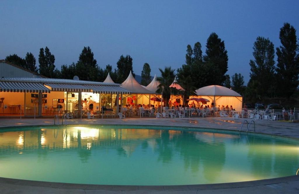 a swimming pool with tables and chairs and a restaurant at Spacieux Mobil-Home Fréjus in Fréjus