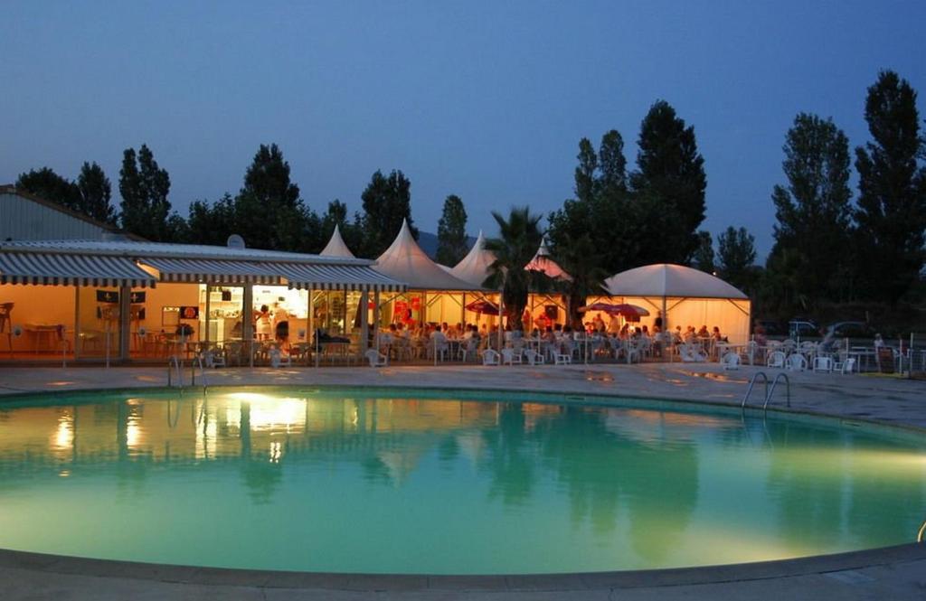 une piscine avec des tables et des chaises ainsi qu'un restaurant dans l'établissement Spacieux Mobil-Home Fréjus, à Fréjus