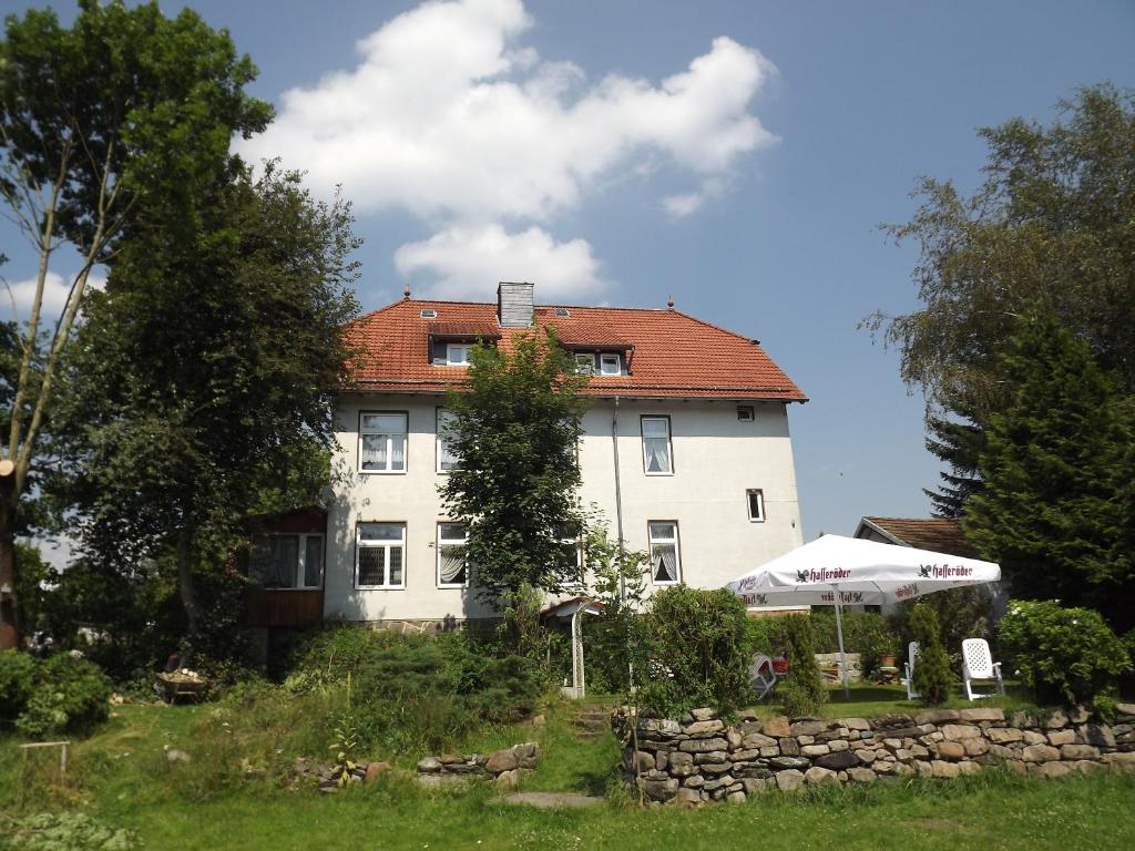 ein großes weißes Haus mit einem Regenschirm davor in der Unterkunft Pension Bodetal in Elend