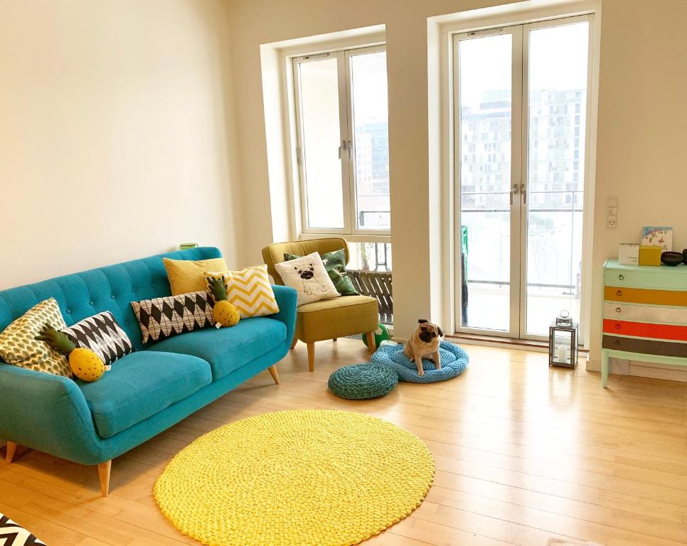 a living room with a blue couch and a dog on a rug at Cute Pug Guest Room in Copenhagen