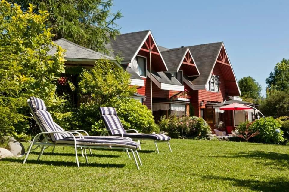 two chairs sitting in the grass in front of a house at Hostal Möller in Villarrica